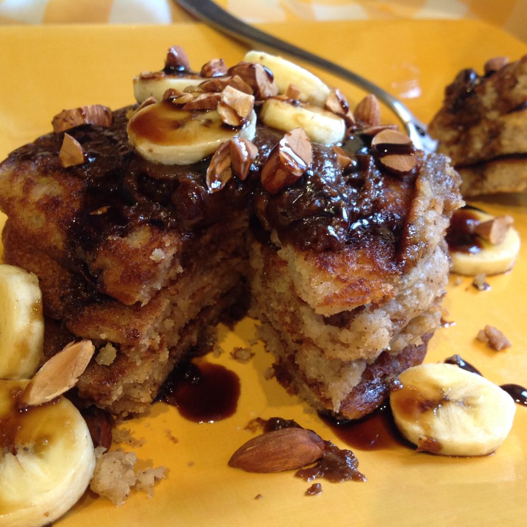 Healthy gluten free protein pancakes topped with banana slices and almonds, made with Gustare Sweet Butter Extra Virgin Olive Oil and Bourbon Maple Balsamic Vinegar