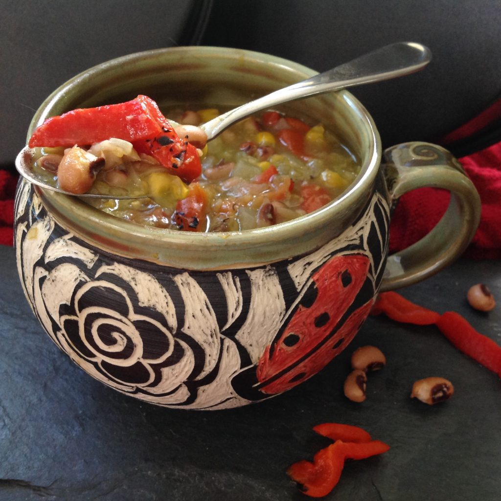 Delicious Black-Eyed Pea and Corn Chowder in a decorative ceramic bowl featuring colorful vegetables and premium Gustare Olive Oil, creating a hearty gourmet meal ready in 30 minutes.
